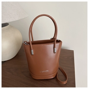 Detail of a brown leather bucket bag with silver hardware and FASHION lettering text