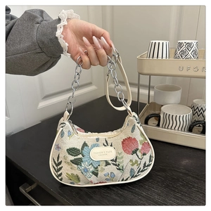 Dettaglio borsa in tela intrecciata a fiori con catena argento e logo in pelle