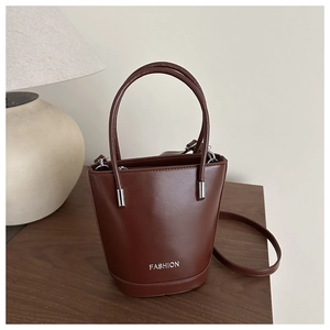 Close-up of dark brown bucket bag with FASHION text and elegant silver metal hardware