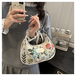 Dettaglio borsa baguette in tela jacquard floreale con catena argento e etichetta