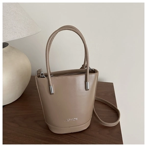 Detail view of khaki bucket bag with cylindrical handles and detachable shoulder strap