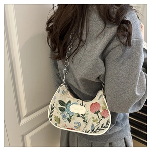 Detail of floral crescent bag with metal chain showing texture and embroidery patterns