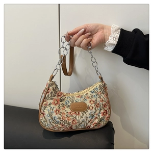Detailed close-up of floral jacquard fabric and brown leather trim on the shoulder bag