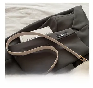 Detail of adjustable beige leather shoulder strap with gold-tone hardware on the small bag