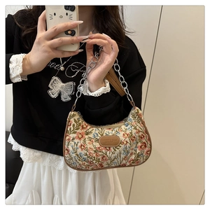 Detail of floral underarm bag with vintage print, brown trim, and metallic chain strap