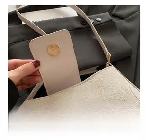 Detail shot of the metal magnetic buckle on the beige minimalist saddle shoulder bag