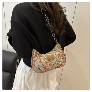 Dettaglio del tessuto jacquard floreale con finiture in pelle marrone e logo sulla borsa