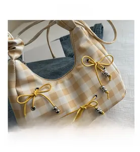 Detail of gingham checkered armpit bag with yellow bow tie and silver metallic beads