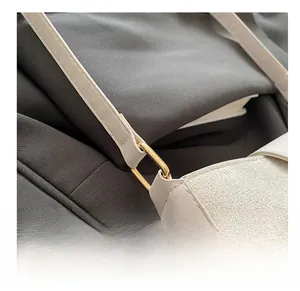 Detail of the golden metal ring buckle and smooth cream leather strap of the shoulder bag
