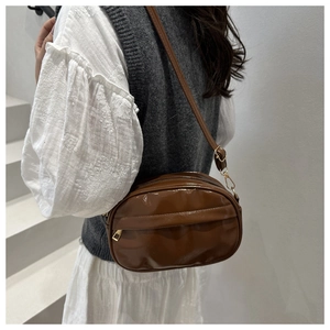 Detail of adjustable shoulder strap and gold-tone zipper on brown crossbody bag