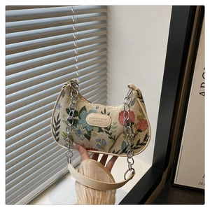Dettaglio della borsa floreale con tracolla a catena e toppa logo in pelle