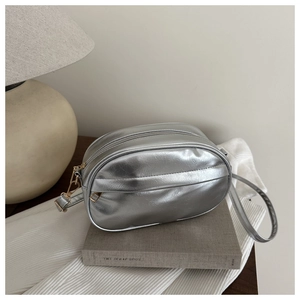 Détail d'un sac bandoulière ovale argenté avec texture métallique froissée