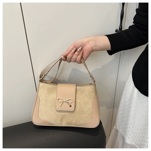 Detail of beige shoulder bag with metallic bow and premium synthetic leather texture