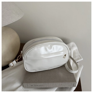 Détail d'un sac bandoulière ovale blanc crème en similicuir brillant avec dorures