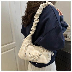 Detail of checkered underarm bag with ruffled strap and decorative bows on blue outfit