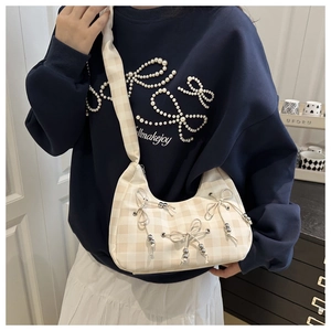 Detailed view of beige checkered crescent bag with decorative bows and silver beads