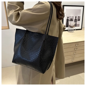 Detail of black crocodile embossed leather tote bag featuring long slim shoulder straps