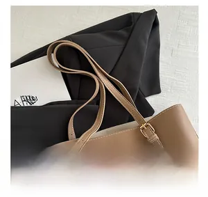 Detail showing khaki tote bag with adjustable strap and fashion ribbon on suit background