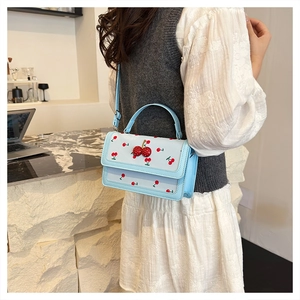 Detail of sweet cherry print pattern and 3D cherry charm on light blue leather crossbody bag