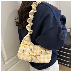 Detail of yellow checkered cloud bag with pleated strap and beaded knot decoration