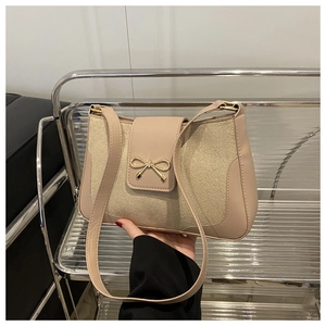 Detail of apricot shoulder bag featuring smooth faux leather and gold bow buckle closure