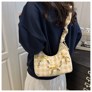Detail showing yellow plaid shoulder bag with bow accents and ruched cloud strap on model