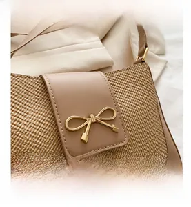 Close-up of woven straw bag with tan leather trim and golden bow buckle detail