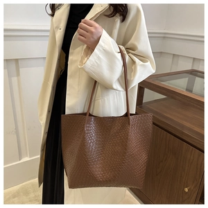 Close-up of brown hand-woven leather tote bag showing large capacity and shoulder strap