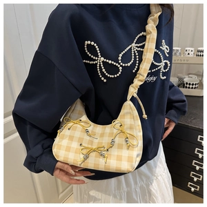 Detail of yellow plaid crescent bag with decorative bows, pearls and ruffled strap