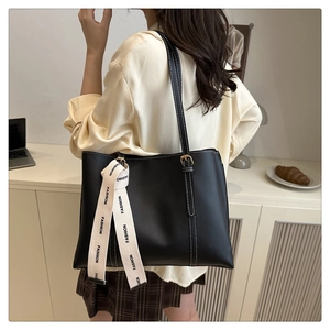 Detail of black large tote bag with white contrast stitching and fashion strap accessory