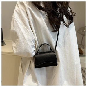 Détail d'un mini sac noir à texture crocodile avec des finitions en argent