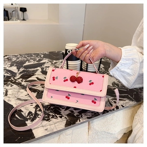 Detail of pink handbag with red cherry print and 3D beaded cherry charm detail