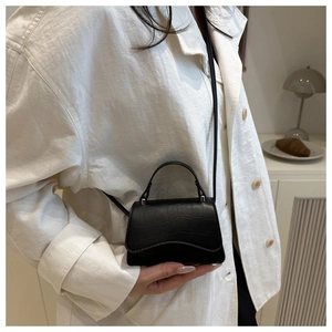 Detail of black faux crocodile pattern leather mini square bag with elegant shoulder strap