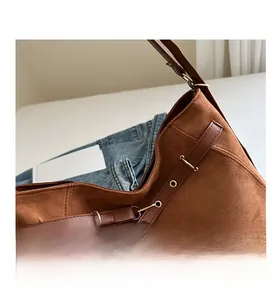 Détail du grand sac cabas en daim marron avec bandoulières en cuir et boucles dorées