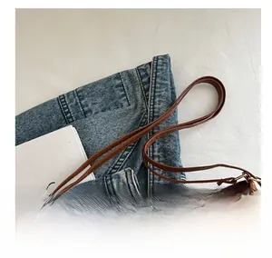 Sac fourre-tout en cuir dépoli marron avec longue bandoulière sur fond de jean