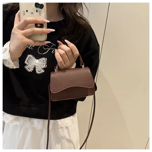 Detailed view of mini dark brown crocodile texture crossbody bag with silver metal parts