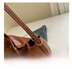 Détail de l'anneau en D doré et des coutures précises sur le sac cabas en daim marron