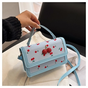 Detail of light blue cherry print bag featuring 3D rhinestone cherry accent on front