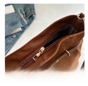 Détail de la fermeture éclair dorée et texture cuir sur un sac cabas marron