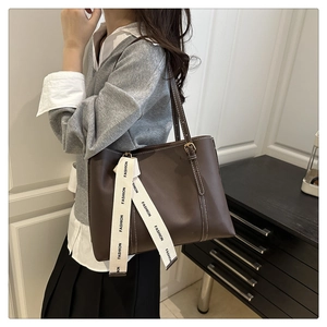 Detail of dark brown tote bag featuring white contrast stitching and fashion ribbon decor