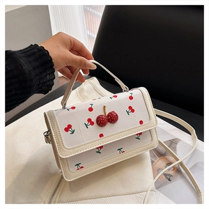 Detailed close-up of cherry pattern handbag with 3D rhinestone cherry buckle