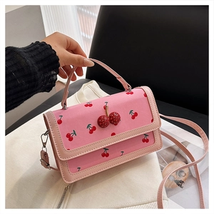 Detail of pink canvas handbag with cherry print and rhinestone pendant embellishment