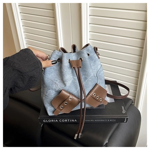 Detail of blue denim bucket bag with brown leather drawstring and metal eyelets