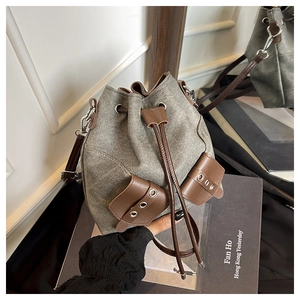 Detail of vintage canvas bucket bag with brown leather front pockets and drawstring