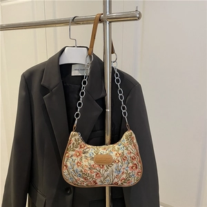 Borsa a spalla vintage con motivo floreale e catena metallica su un blazer grigio