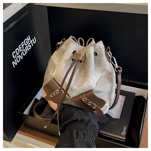 Detailed view of canvas bucket bag with brown leather drawstring and silver hardware
