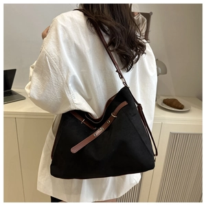 Close-up of large black tote bag with brown straps and gold hardware on shoulder