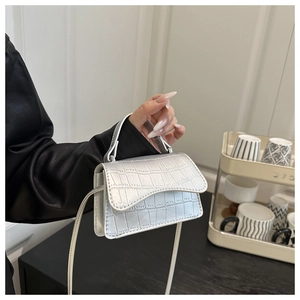 Detail of silver crocodile-embossed mini handbag held by hand with slim strap