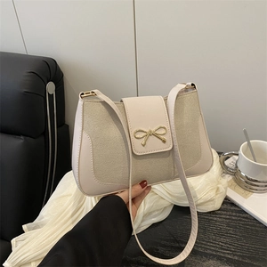 Chic two-tone shoulder bag with beige leather and golden bow clasp on a textured strap