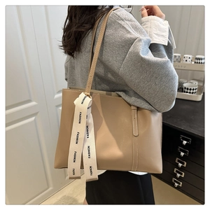 Dettaglio della borsa tote in pelle beige con ciondolo FASHION portata a spalla